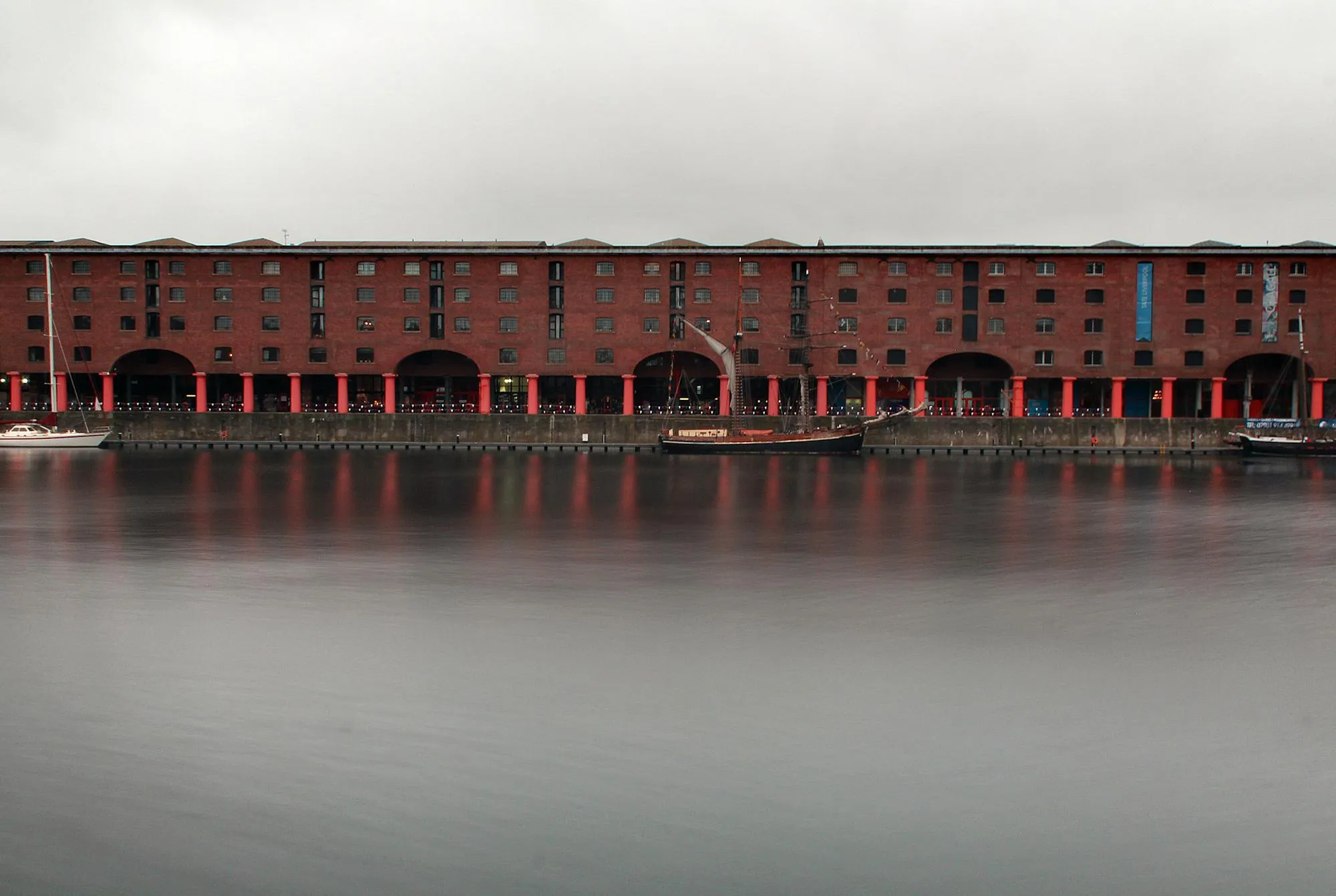 The Royal Albert Dock buildings in Liverpool, weather-darkened brick, Mersey water in the foreground